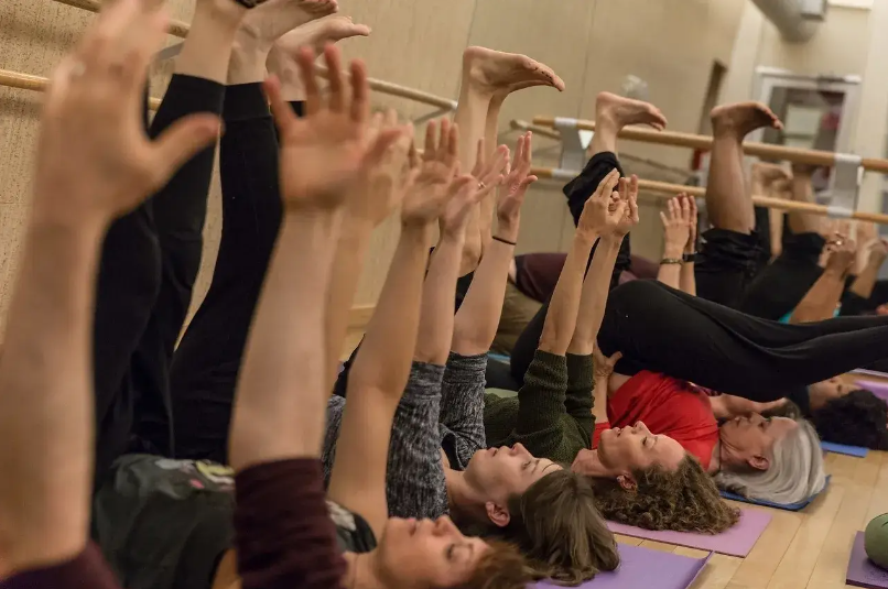 the whole room on mats, arms and legs reaching up
